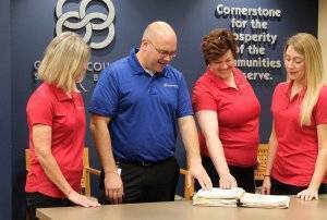 A group of GCSB employees smile and look over paperwork.